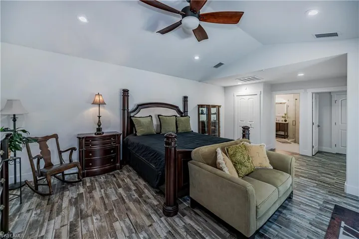 Bedroom featuring wood finished floors, lofted ceiling, recessed lighting, and ensuite bathroom