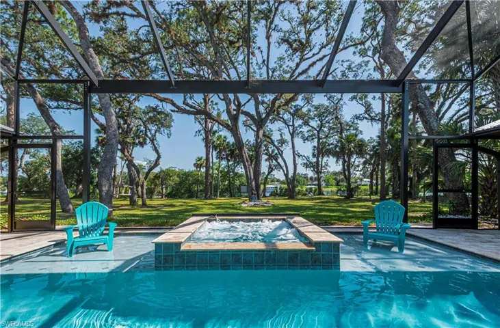 Swimming pool with an in-ground hot tub, glass enclosure, and a patio