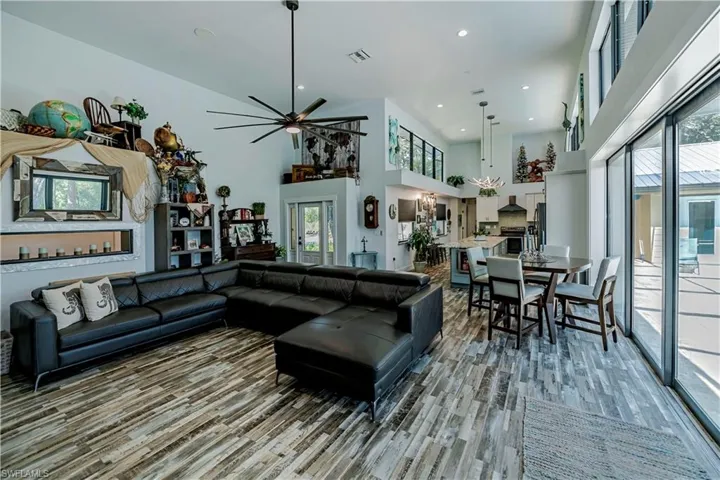Living area with healthy amount of natural light, light wood finished floors, a high ceiling, ceiling fan, and recessed lighting