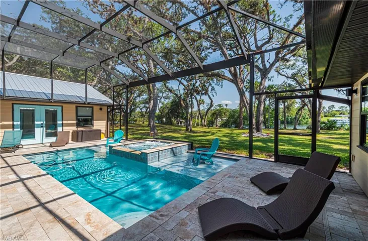 View of pool with a patio area, a lawn, french doors, and a pool with connected hot tub