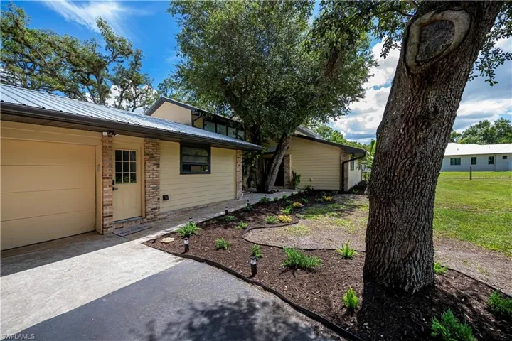 View of front facade featuring a metal roof, driveway, and a garage