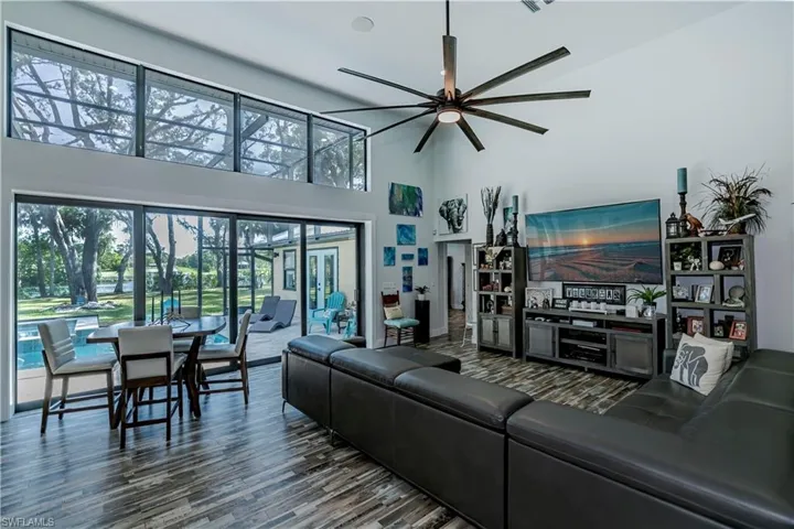 Living area featuring a ceiling fan, a towering ceiling, and wood finished floors