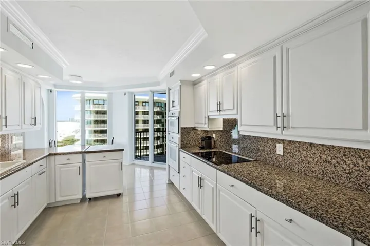 Large kitchen featuring white cabinets, granite countertops, and upgraded appliances