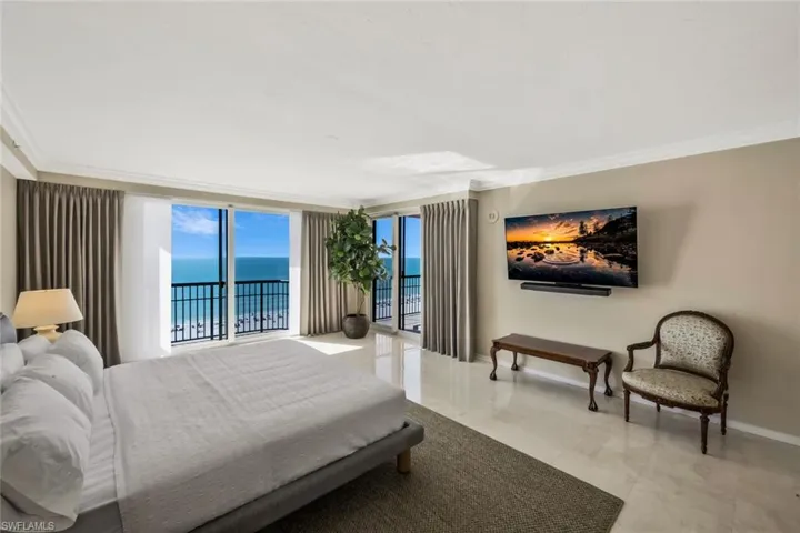 Very large Primary Bedroom with balcony access featuring wide water and beach views.