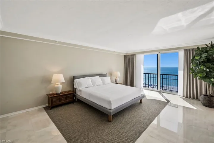Very large Primary Bedroom with balcony access featuring wide water and beach views.