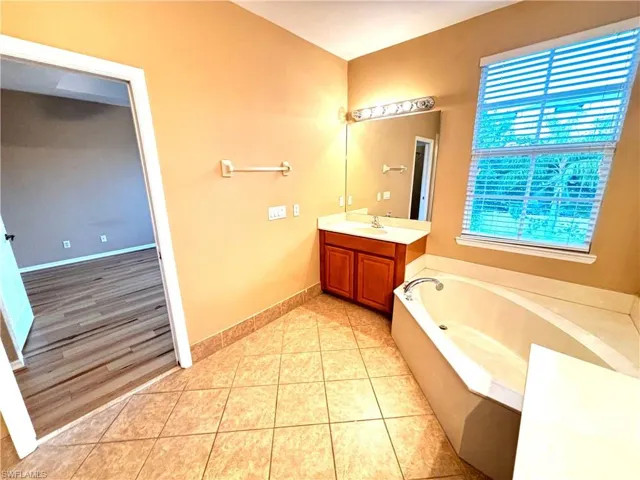 Bathroom featuring vanity, a bath, and light tile patterned flooring