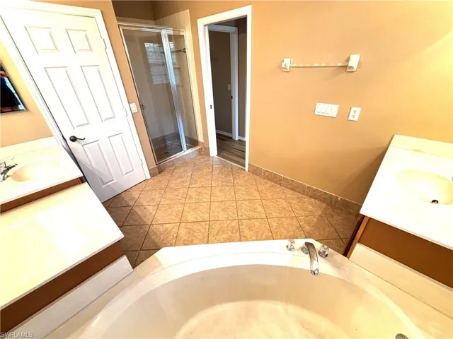 Bathroom with two vanities, a stall shower, and a bath