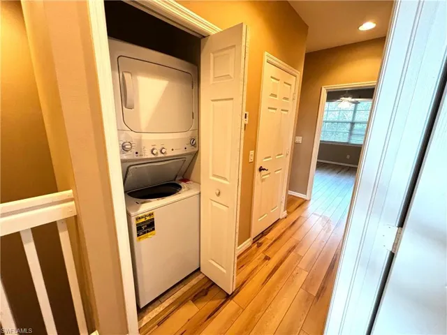Laundry area featuring stacked washer / drying machine, light wood-style flooring, and recessed lighting