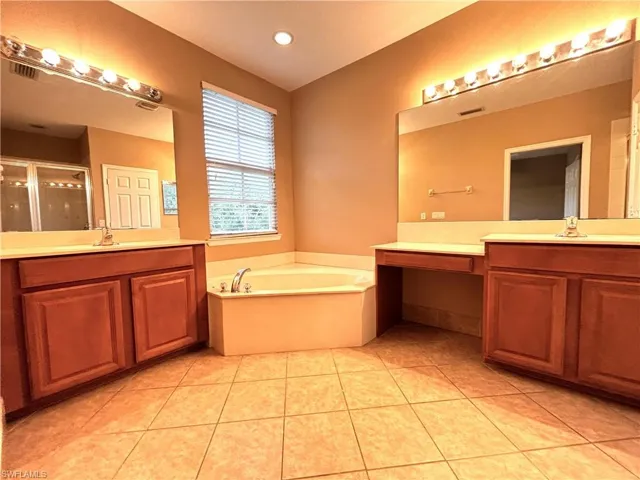 Bathroom with two vanities, a stall shower, a garden tub, light tile patterned floors, and recessed lighting