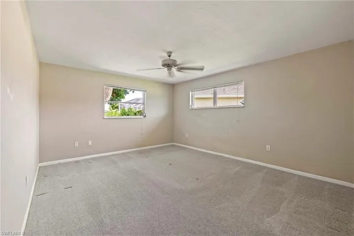 Carpeted empty room with ceiling fan and a healthy amount of sunlight