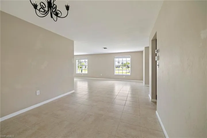 Tiled empty room featuring a notable chandelier