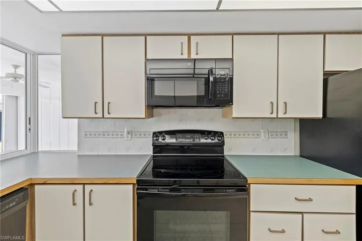 Kitchen featuring black appliances, tasteful backsplash, white cabinetry, and ceiling fan
