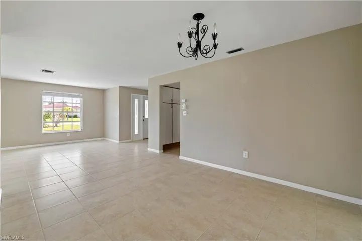 Tiled spare room featuring a chandelier