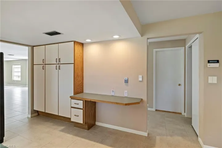 Kitchen featuring white cabinets, kitchen peninsula, built in desk, and light tile patterned floors