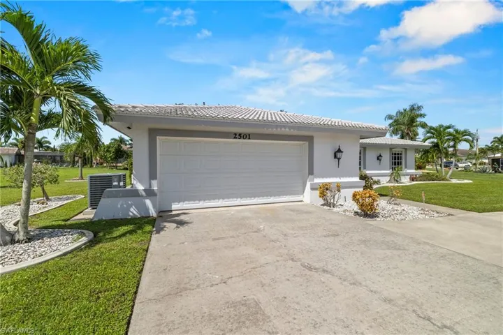 View of front of home featuring central AC unit, a garage, and a front lawn