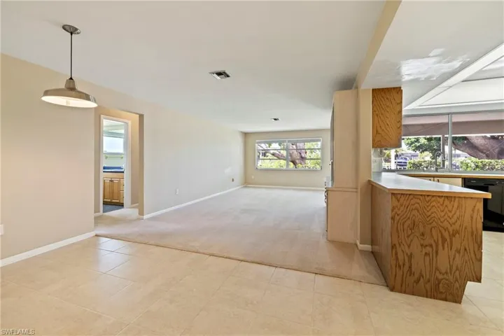 Kitchen featuring light colored carpet, decorative light fixtures, and kitchen peninsula
