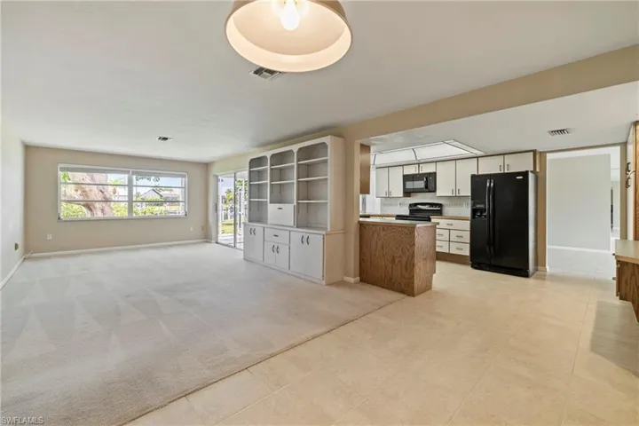 Kitchen with white cabinetry, light colored carpet, and black appliances