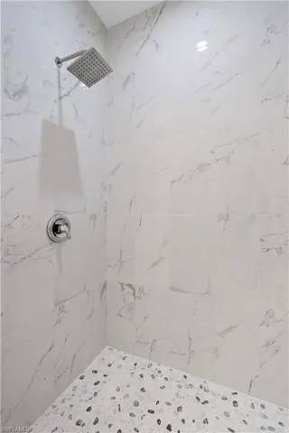 Full bath with a marble finish shower