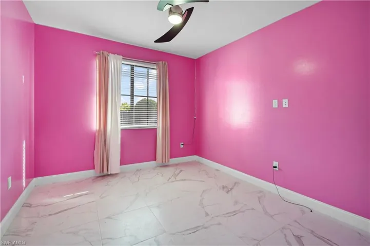 Empty room featuring light marble finish floors and a ceiling fan