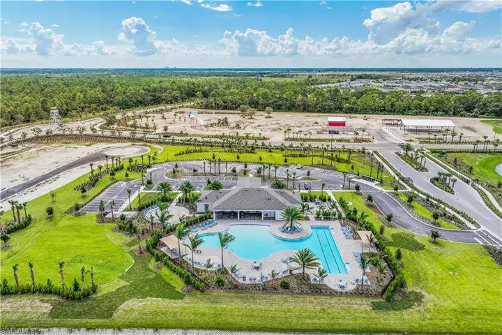 Resort-style pool area featuring a clubhouse, multiple swimming pools, palm trees, and lounge seating