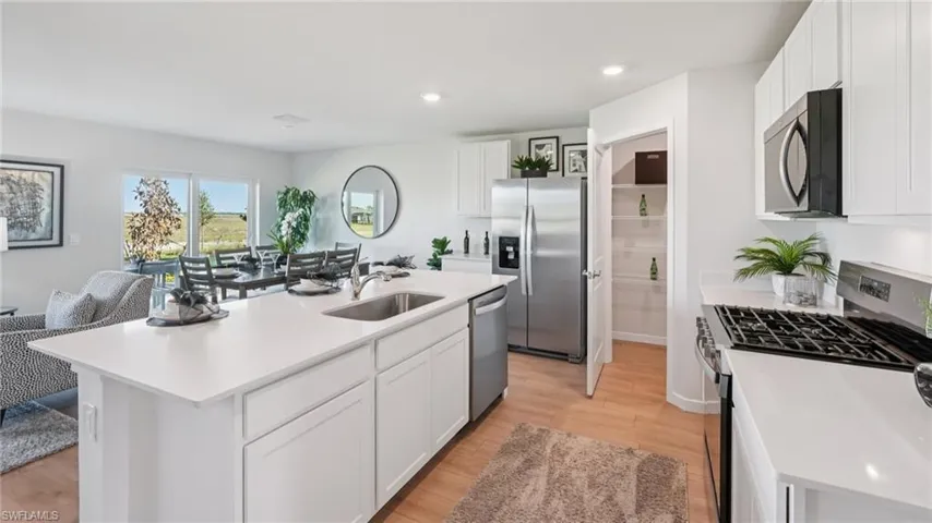 Modern kitchen with a spacious island featuring an undermount sink, white cabinetry, stainless steel appliances, and a gas range