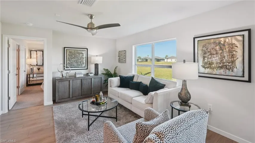 Open living area featuring wood-finish flooring, a contemporary ceiling fan, and large windows providing abundant natural light