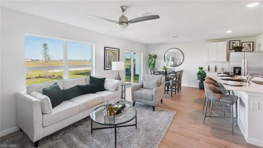 Open-concept living space featuring wood-finish flooring, a contemporary ceiling fan, and large windows