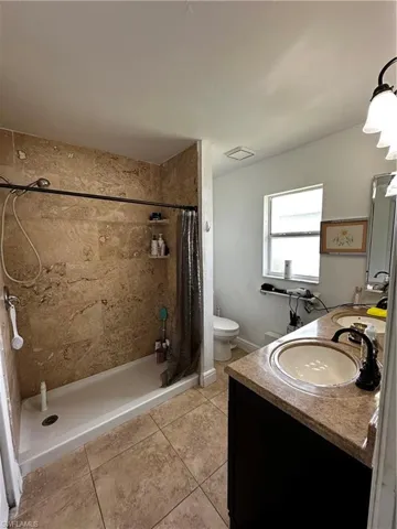Bathroom with vanity, tile patterned floors, a stall shower, and toilet