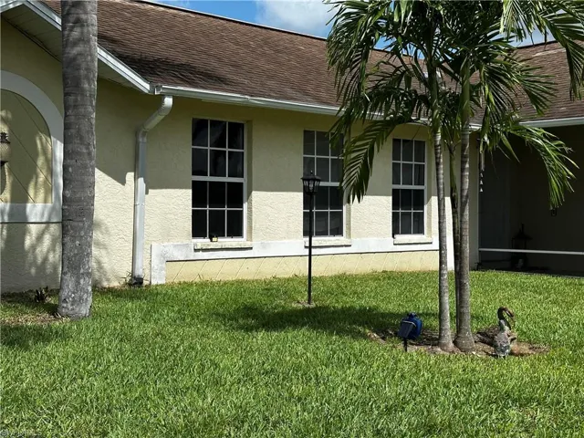 View of home's exterior with stucco siding, a lawn, and roof with shingles