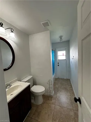 Full bath with vanity, toilet, tile patterned floors, and shower / bath combo with shower curtain