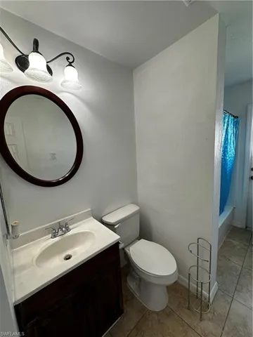 Bathroom featuring vanity, tile patterned flooring, toilet, and shower / tub combo with curtain