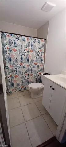 Master Bathroom featuring a white vanity with integrated sink, a toilet, and tiled flooring