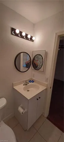Master Compact bathroom featuring a Corner Vanity with integrated sink, chrome faucet, and white cabinetry