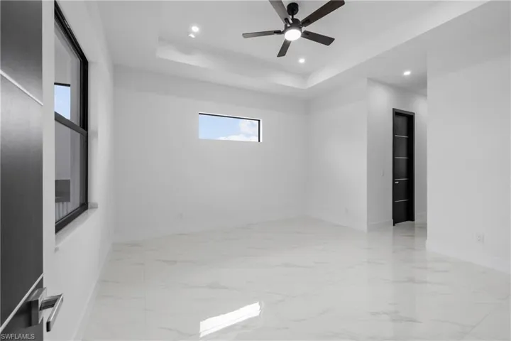Empty room featuring recessed lighting, marble finish flooring, a tray ceiling, and ceiling fan