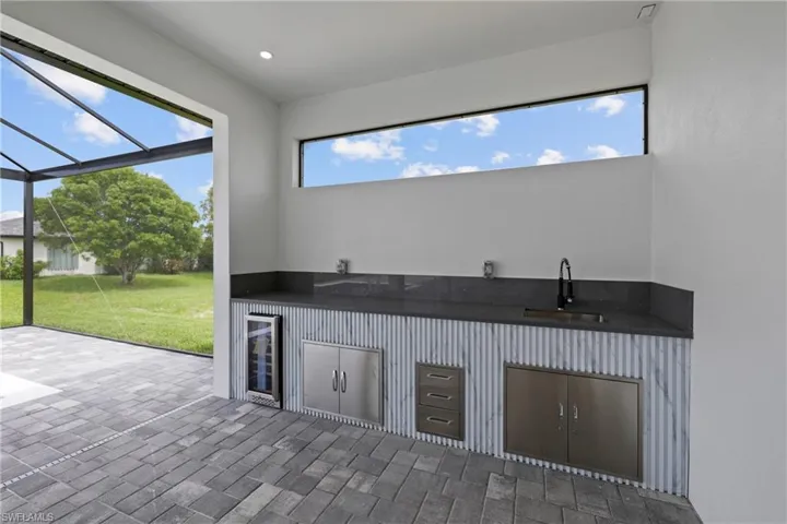 View of patio / terrace featuring exterior kitchen, beverage cooler, and glass enclosure
