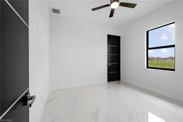 Empty room with ceiling fan and marble look tile flooring