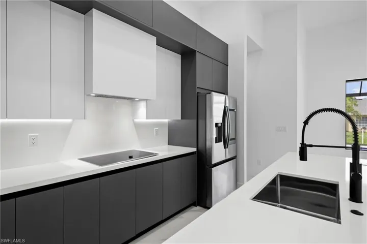 Kitchen with black electric stovetop, modern cabinets, and light countertops