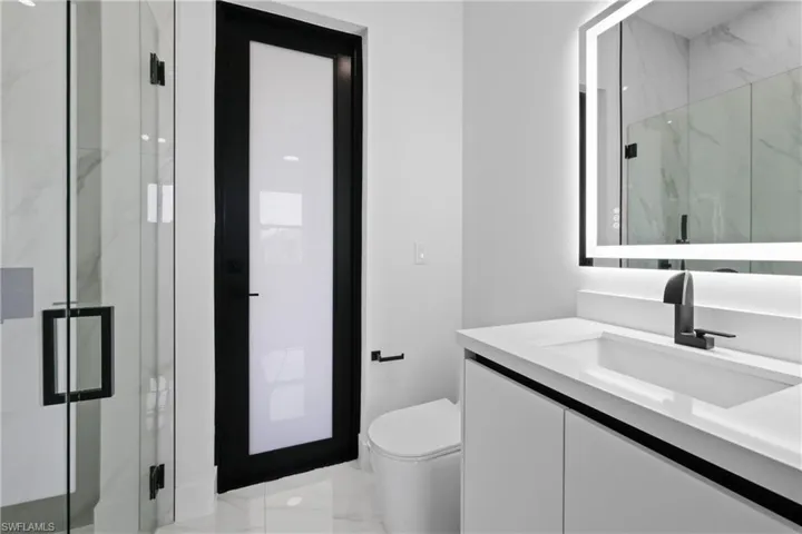 Bathroom featuring vanity, a marble finish shower, and marble look tiles