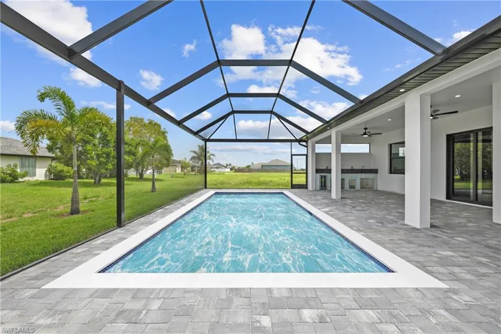 Swimming pool with a lawn, a ceiling fan, a patio area, and glass enclosure