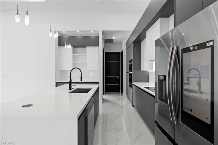 Kitchen featuring stainless steel fridge, modern cabinets, open shelves, light marble finish floors, and light countertops