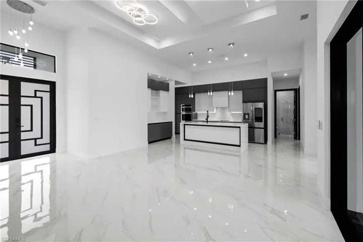 Kitchen with appliances with stainless steel finishes, modern cabinets, a tray ceiling, light marble finish floors, and recessed lighting