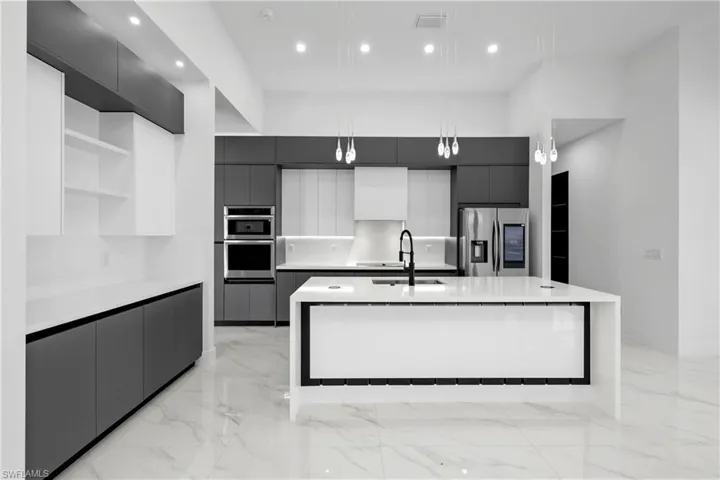 Kitchen with stainless steel appliances, modern cabinets, open shelves, a kitchen island with sink, and recessed lighting