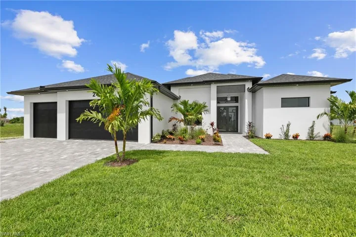 Prairie-style home with an attached garage, decorative driveway, stucco siding, and a front lawn