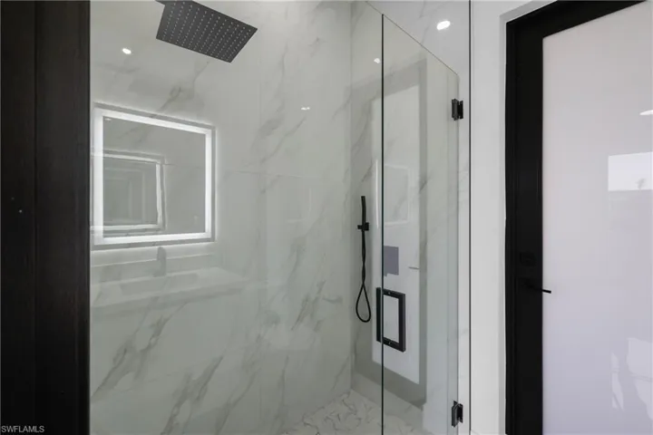 Full bath with a marble finish shower
