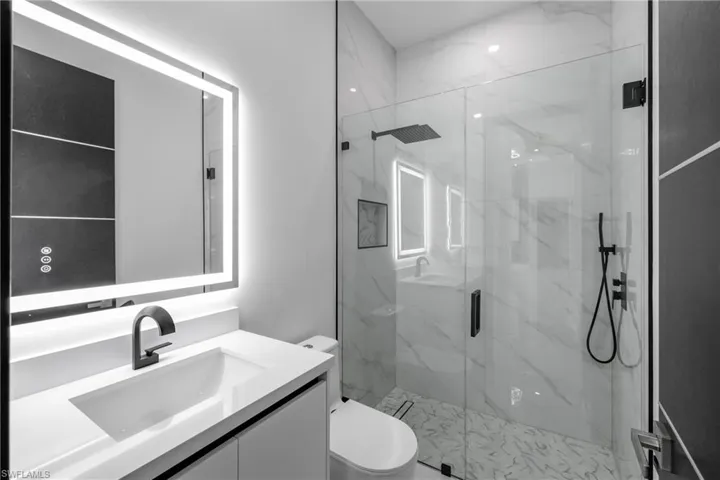 Bathroom featuring a marble finish shower and vanity