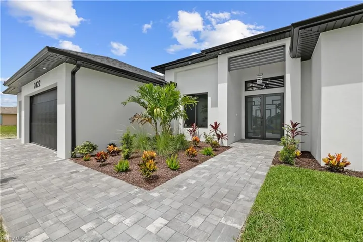 Doorway to property featuring french doors, stucco siding, a garage, and decorative driveway