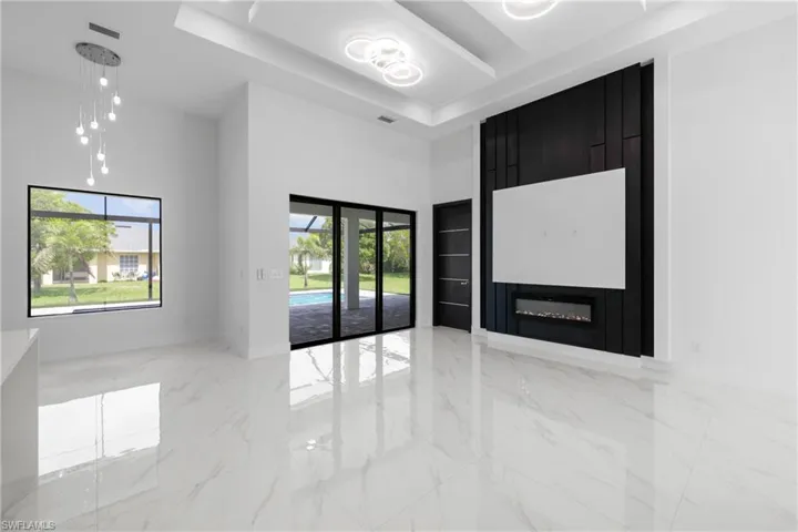 Empty room with a high ceiling, marble tiled flooring, and a raised ceiling