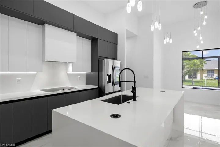 Kitchen featuring light marble finish flooring, modern cabinets, and a towering ceiling