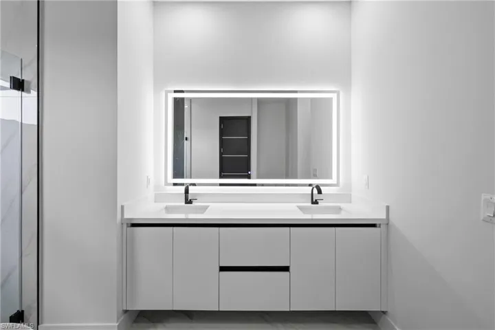Full bath with double vanity and a shower stall