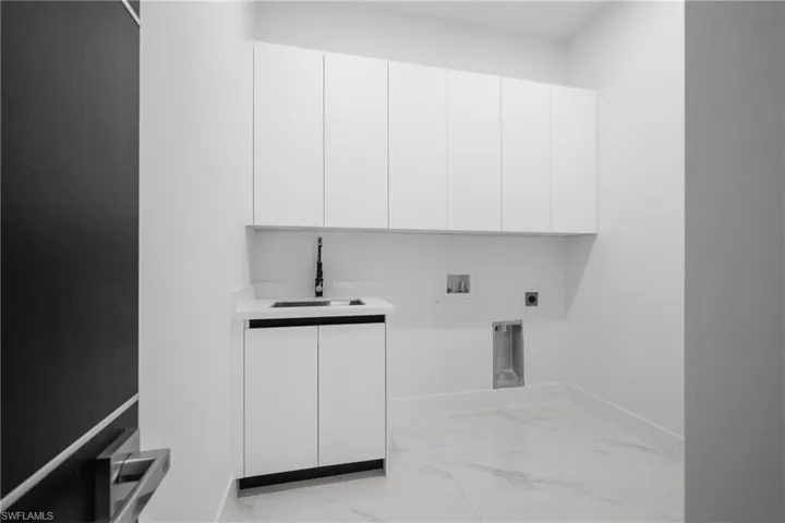 Laundry room featuring electric dryer hookup, cabinet space, light marble finish floors, and washer hookup